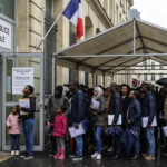 Une file d'attente de demandeurs d'asile devant la préfecture de police à Paris sous la pluie.